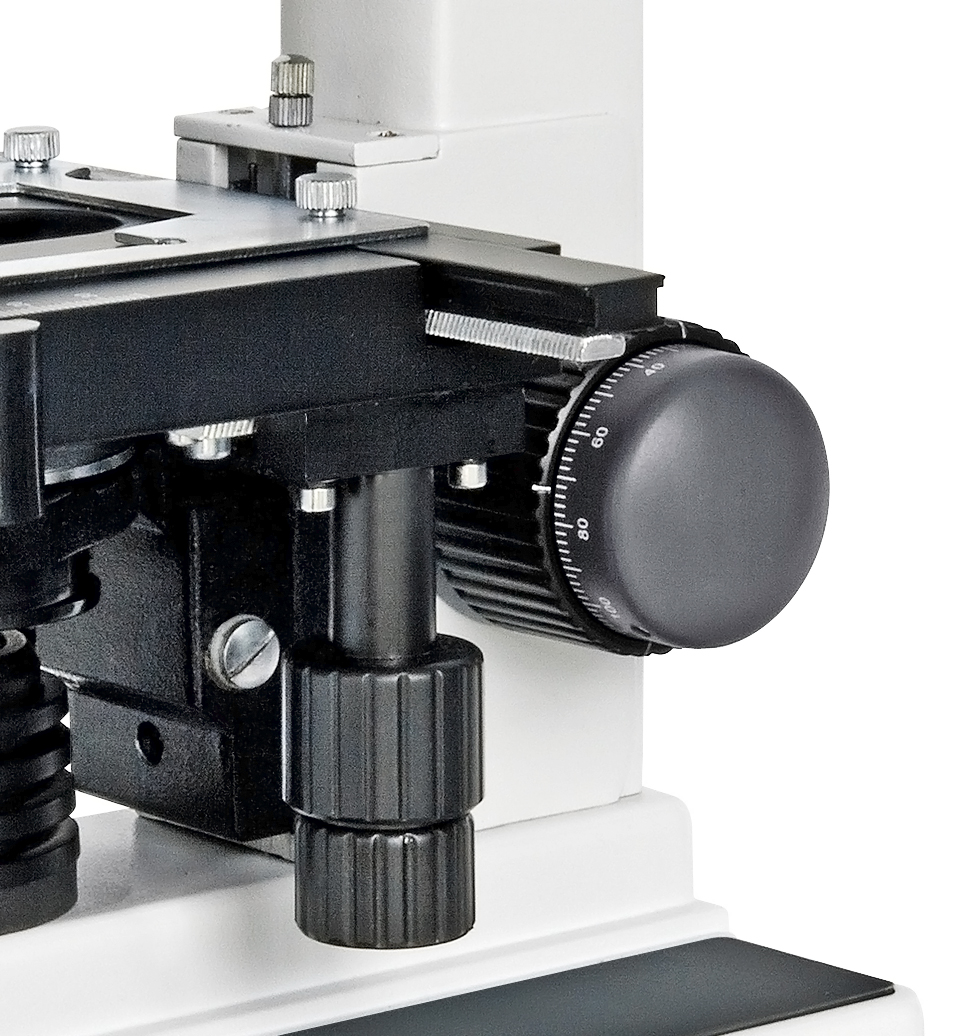 Primer plano de la platina mecánica y las perillas de ajuste de un microscopio.
