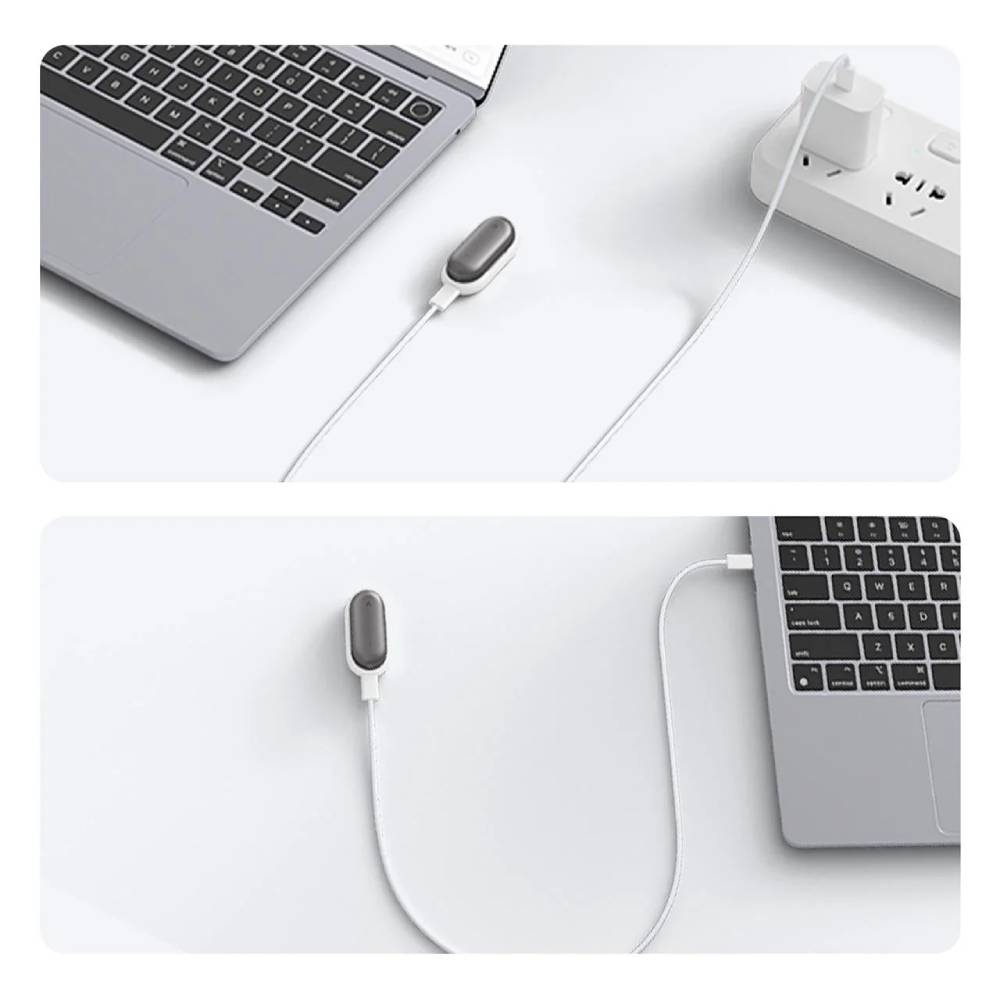 Ein kleines graues Gadget ist mit einem weißen Kabel an einen Laptop und eine Steckdosenleiste angeschlossen.