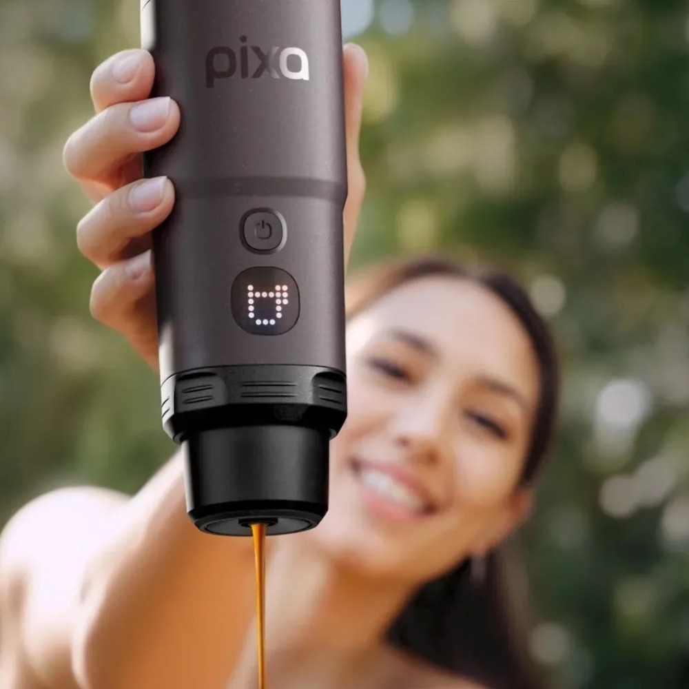 Eine Frau hält eine schwarze Pixa-Kaffeemaschine, aus der frischer Kaffee fließt.
