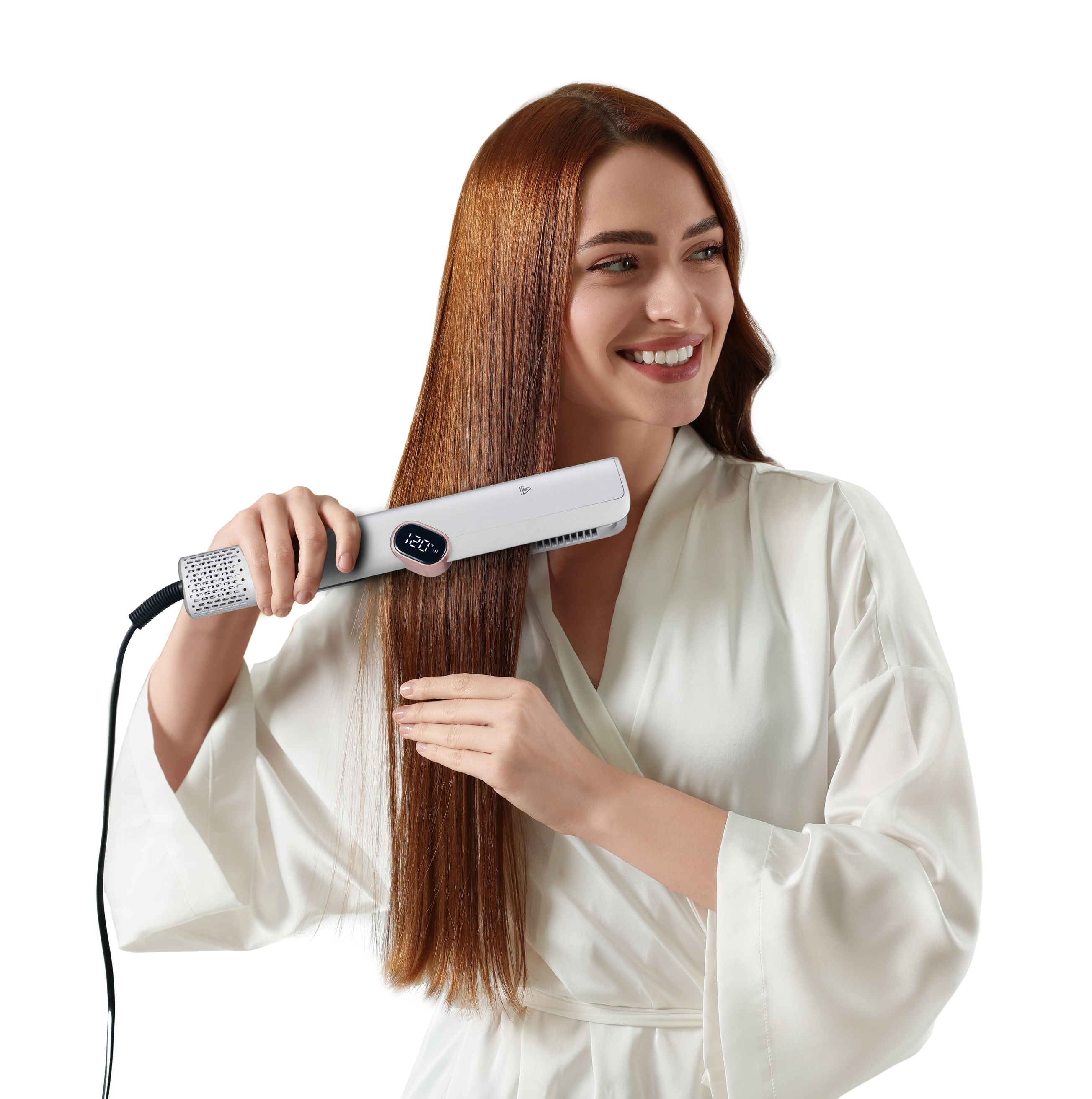 Una donna sorridente in vestaglia bianca si liscia i lunghi capelli castani con una piastra argentata su sfondo bianco.