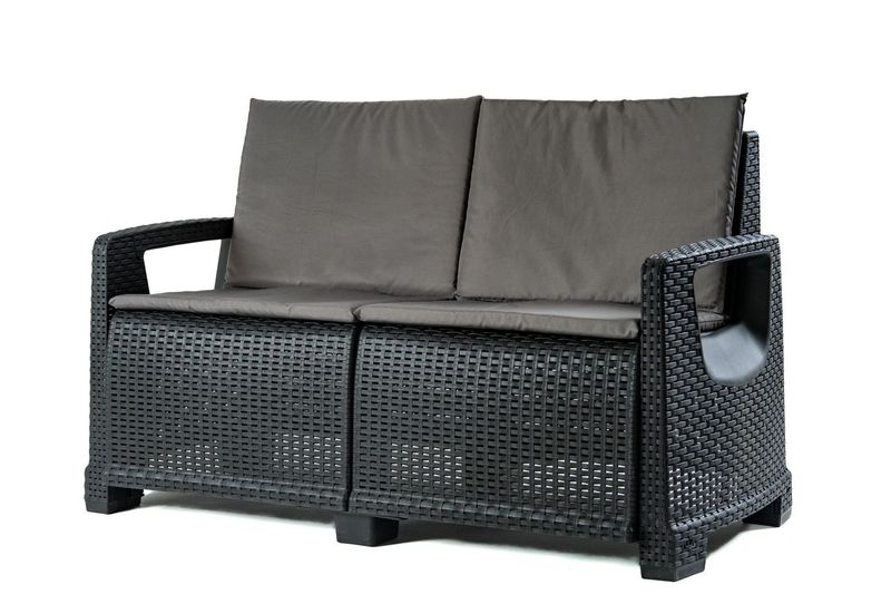 Czarna sofa ogrodowa z rattanu z szarymi poduszkami na białym tle.