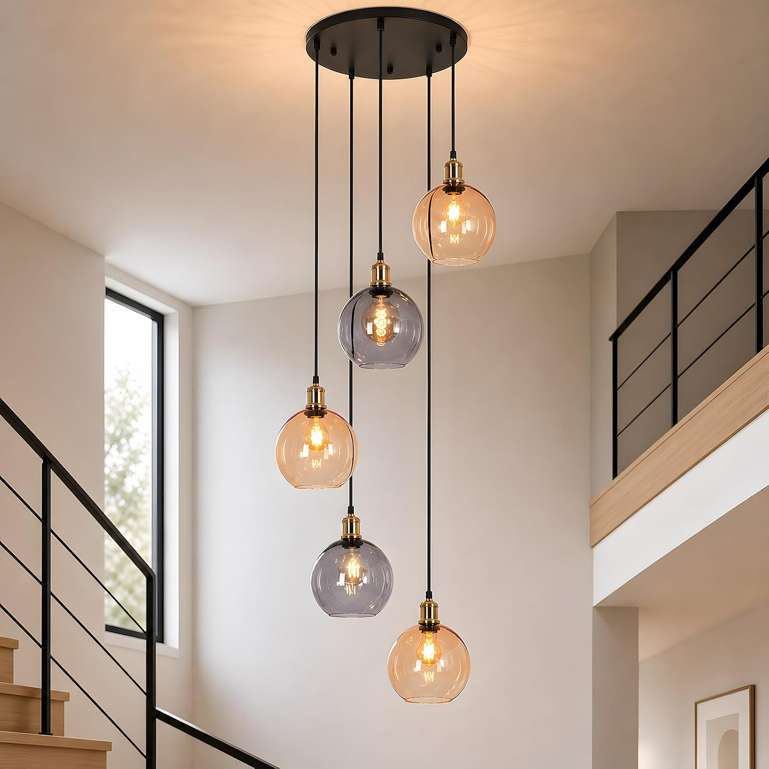 Una lámpara de techo moderna con cinco globos de vidrio colgantes en ámbar y gris, iluminando una escalera.