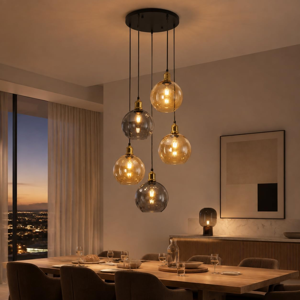 Un comedor moderno cuenta con una lámpara colgante sobre una mesa de madera, con luces de la ciudad por una ventana.