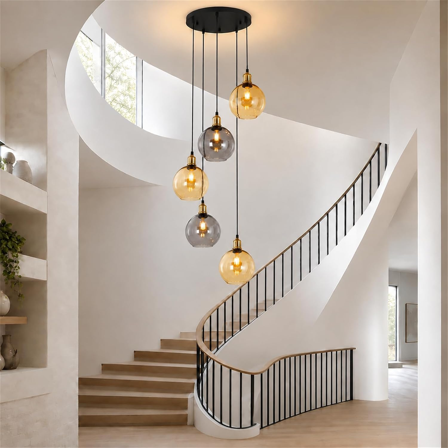 Lámpara colgante moderna con esferas de vidrio ámbar y gris sobre una escalera curva.
