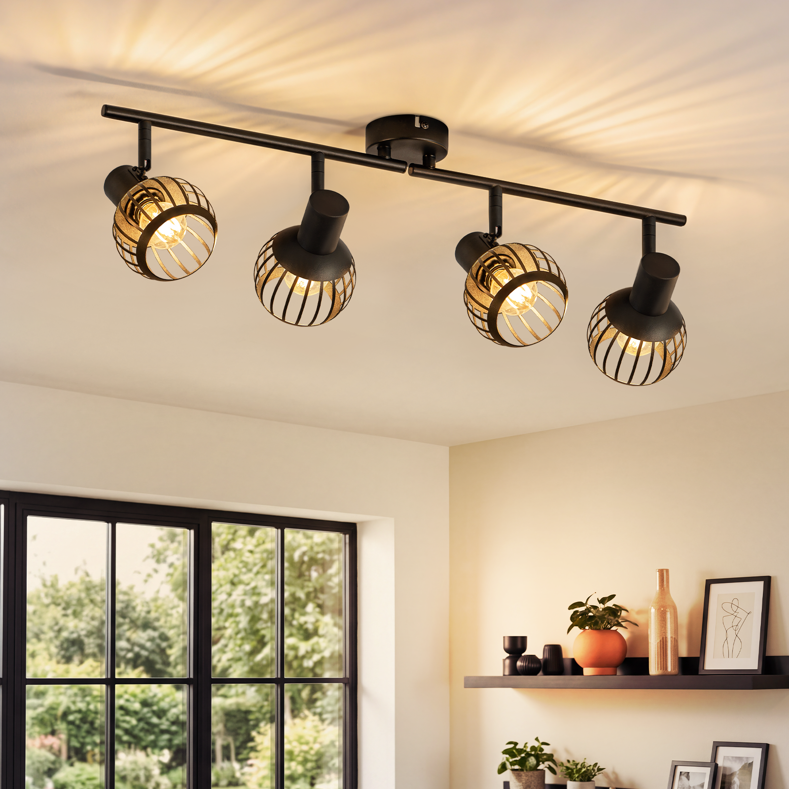 Czarna lampa sufitowa z czterema obrotowymi reflektorami i drucianymi kloszami w nowoczesnym salonie.