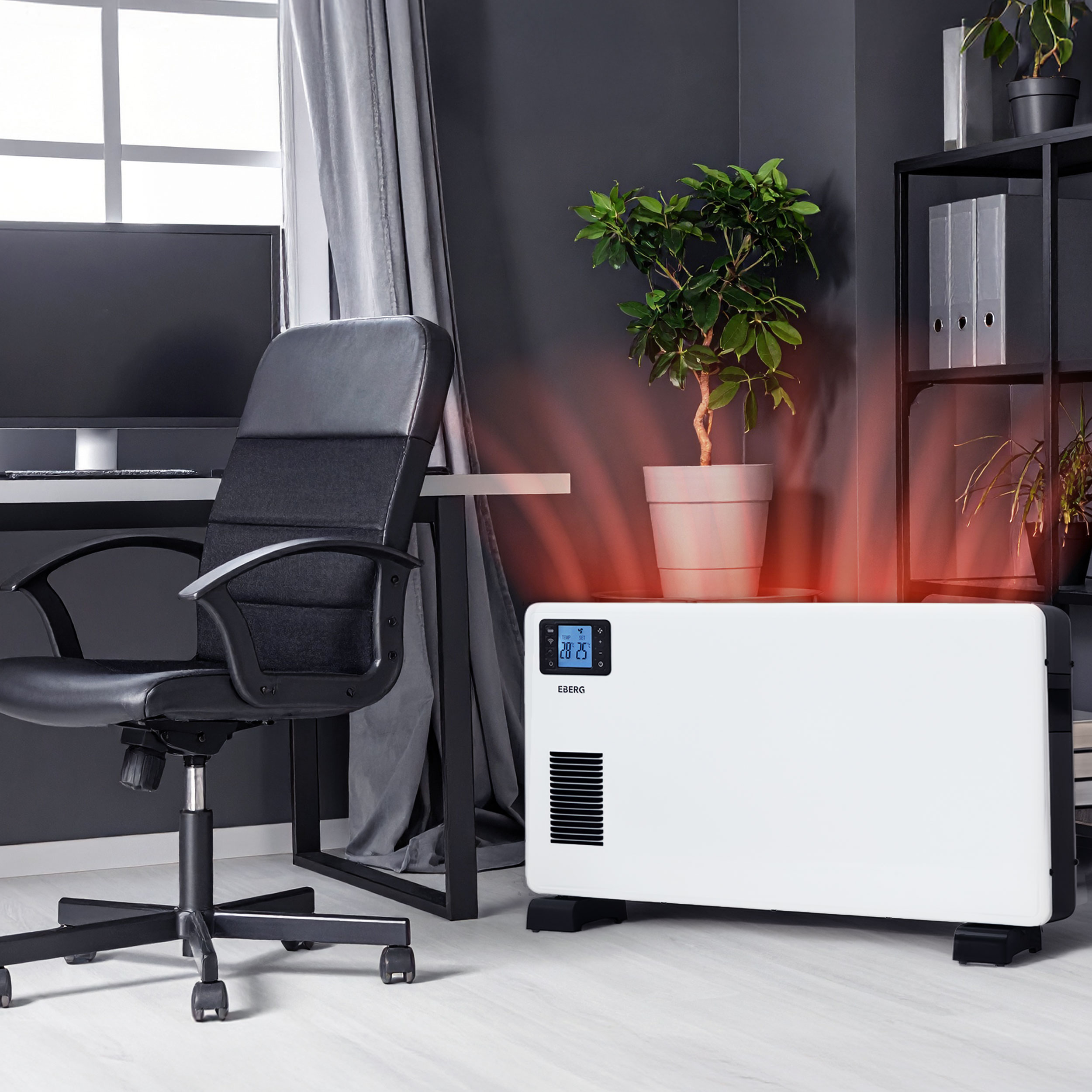 Biały grzejnik elektryczny w nowoczesnym biurze emituje ciepło przy szarej ścianie obok biurka.