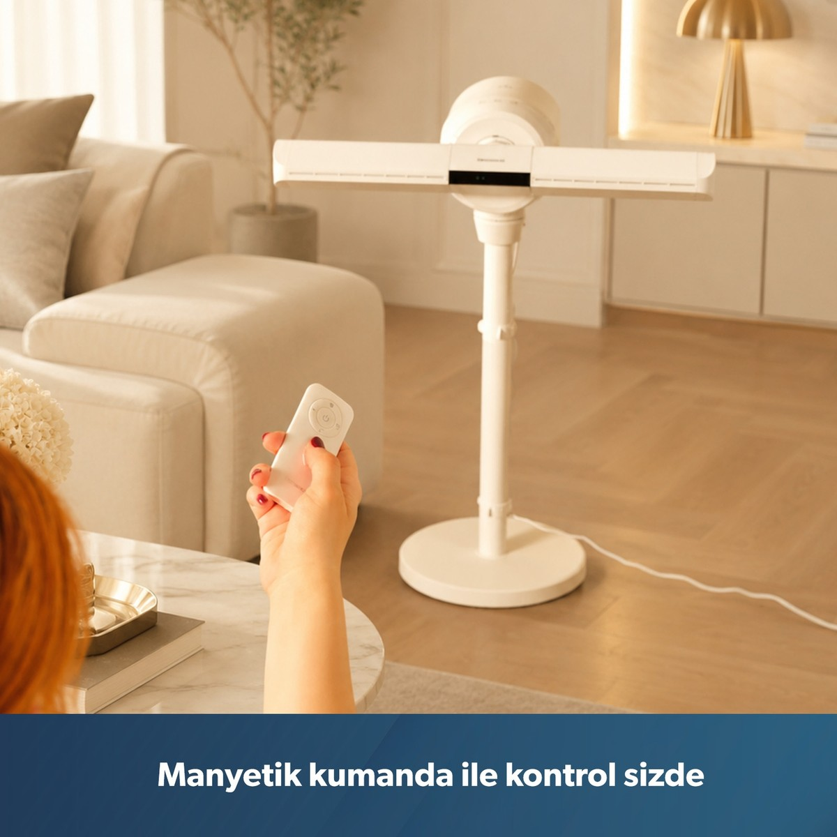 Aydınlık bir oturma odasında beyaz kumanda tutan bir kişi, modern ayaklı vantilatörü kontrol ediyor.