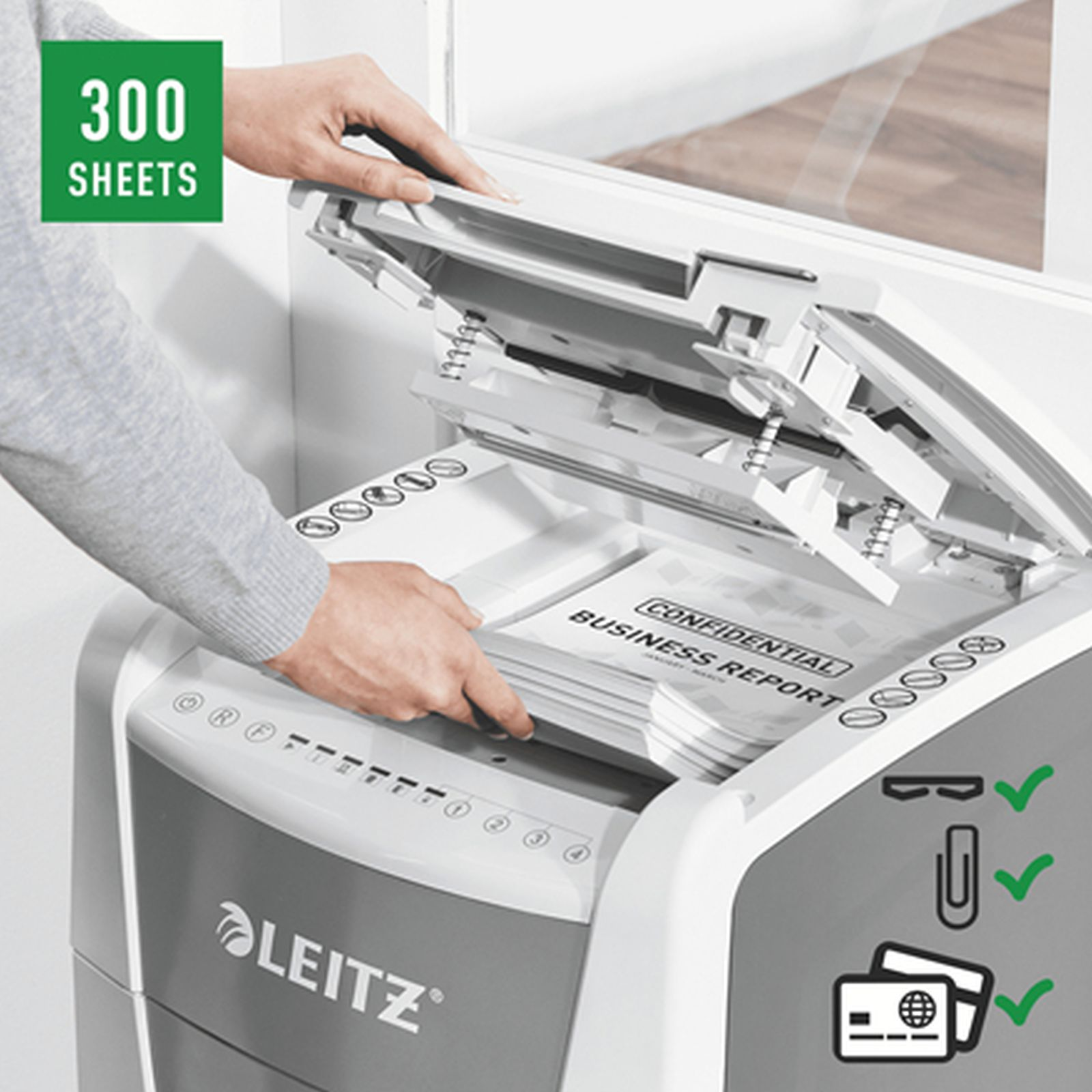 Eine Person legt Papier in einen weißen Leitz Aktenvernichter für bis zu 300 Blatt.