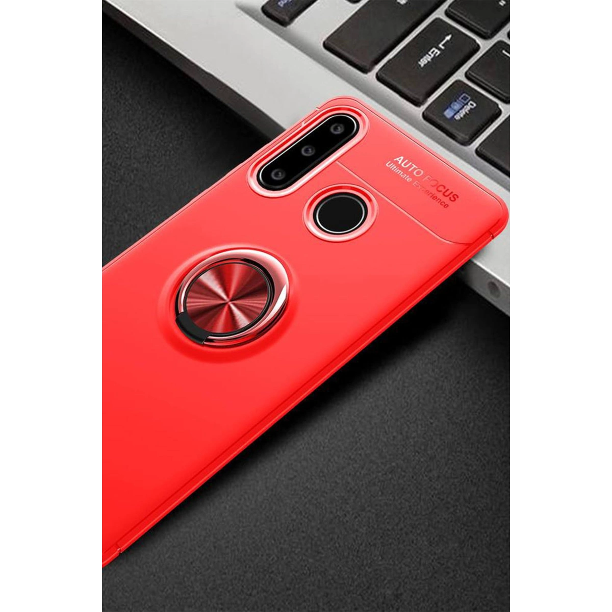 Halka tutuculu ve kamera kesikli kırmızı telefon kılıfı, laptop klavyesinin önünde duruyor.