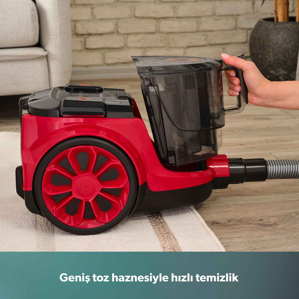 Bir el, kırmızı renkli elektrikli süpürgenin toz haznesini çıkarıyor.