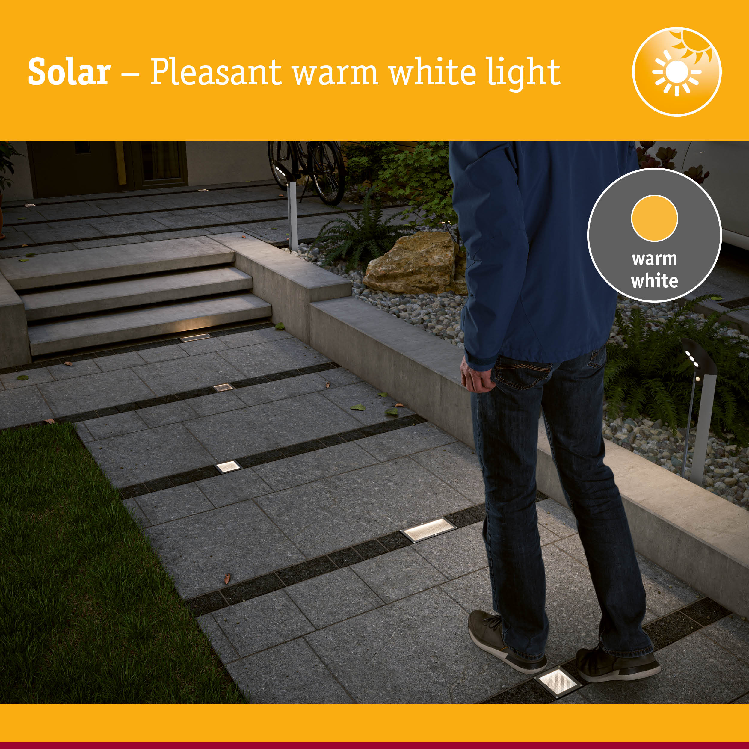 Ein Mann steht auf einem gepflasterten Weg im Garten, der mit warmweißen Solarleuchten beleuchtet wird.