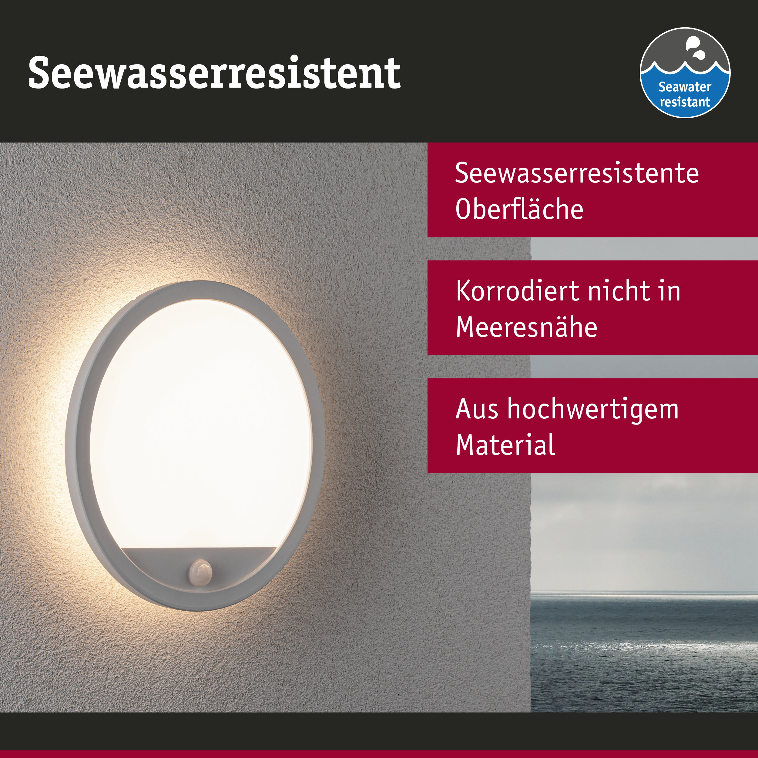 Eine runde, seewasserbeständige Wandleuchte ist an einer strukturierten grauen Wand montiert, im Hintergrund das Meer.
