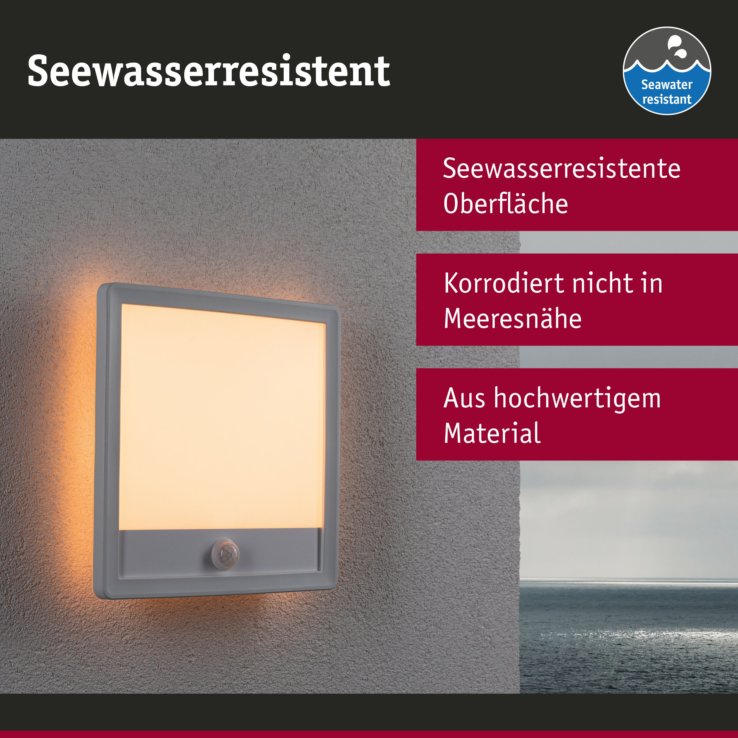 Eine quadratische, graue Wandleuchte mit Bewegungsmelder leuchtet warm an einer grauen Wand mit Blick aufs Meer.