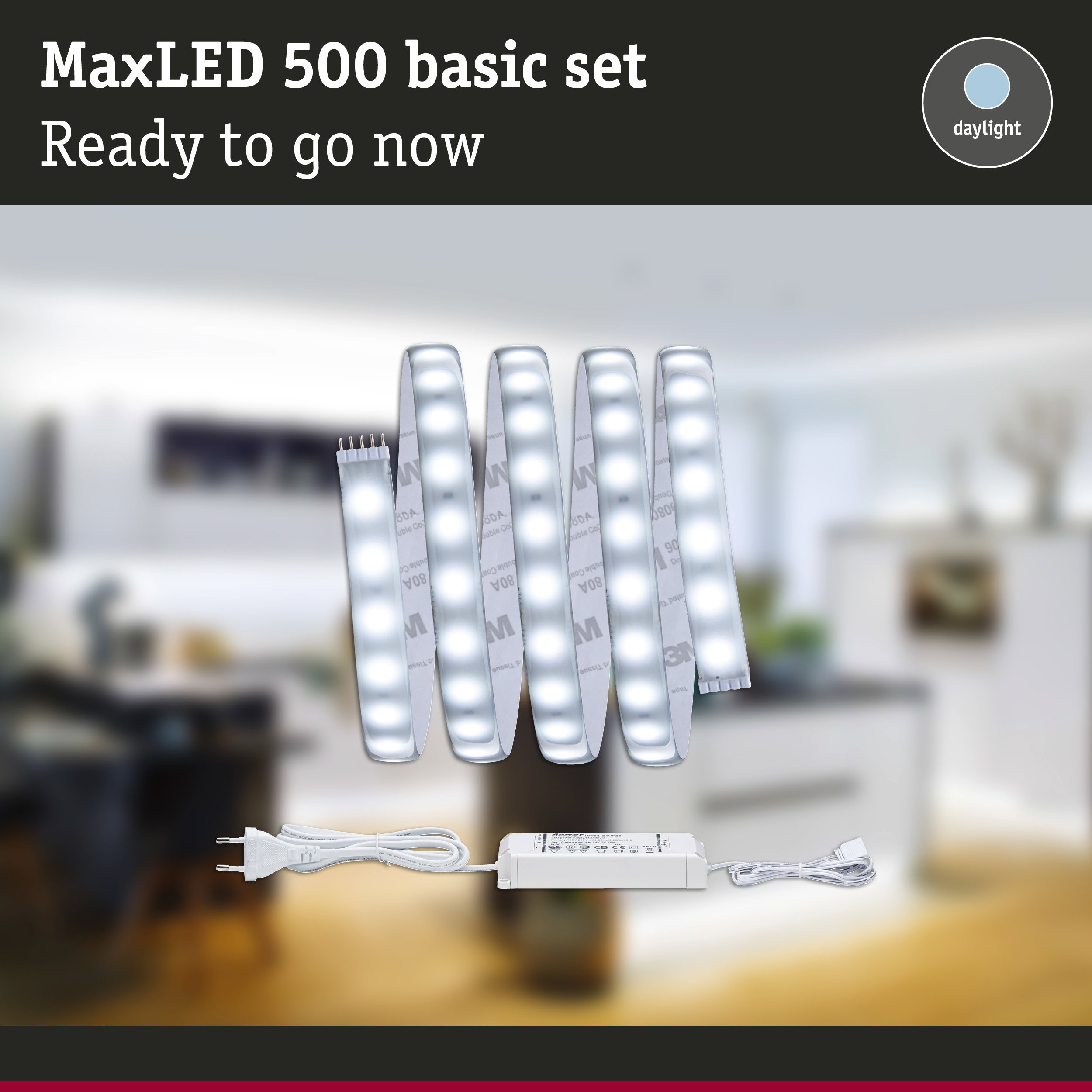 MaxLED 500 LED-Streifen im Grundset mit Netzteil und Stecker vor verschwommenem Innenraum.