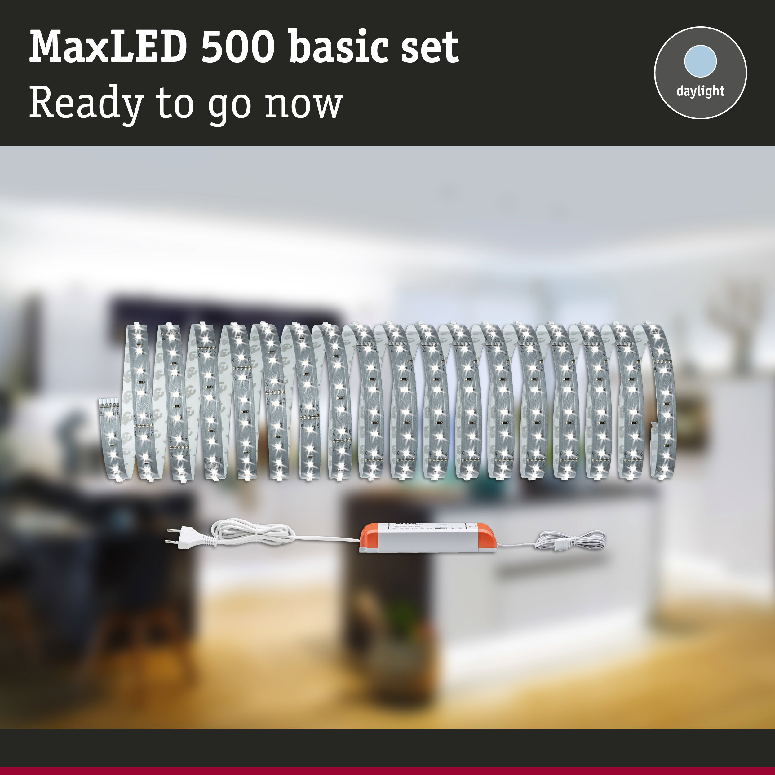 MaxLED 500 Basis-Set mit beleuchtetem LED-Streifen und Netzteil vor verschwommenem Hintergrund.