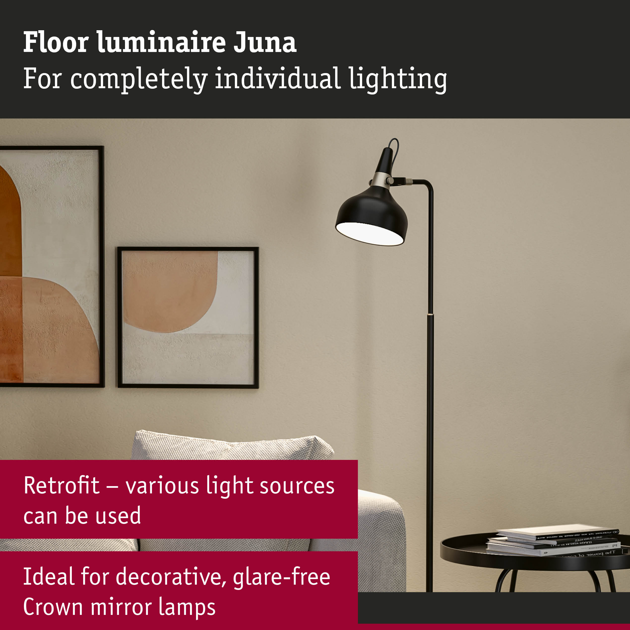 Eine schwarze Stehlampe steht neben einem Sofa und einem Tisch mit Büchern, gerahmte Kunst an der Wand.