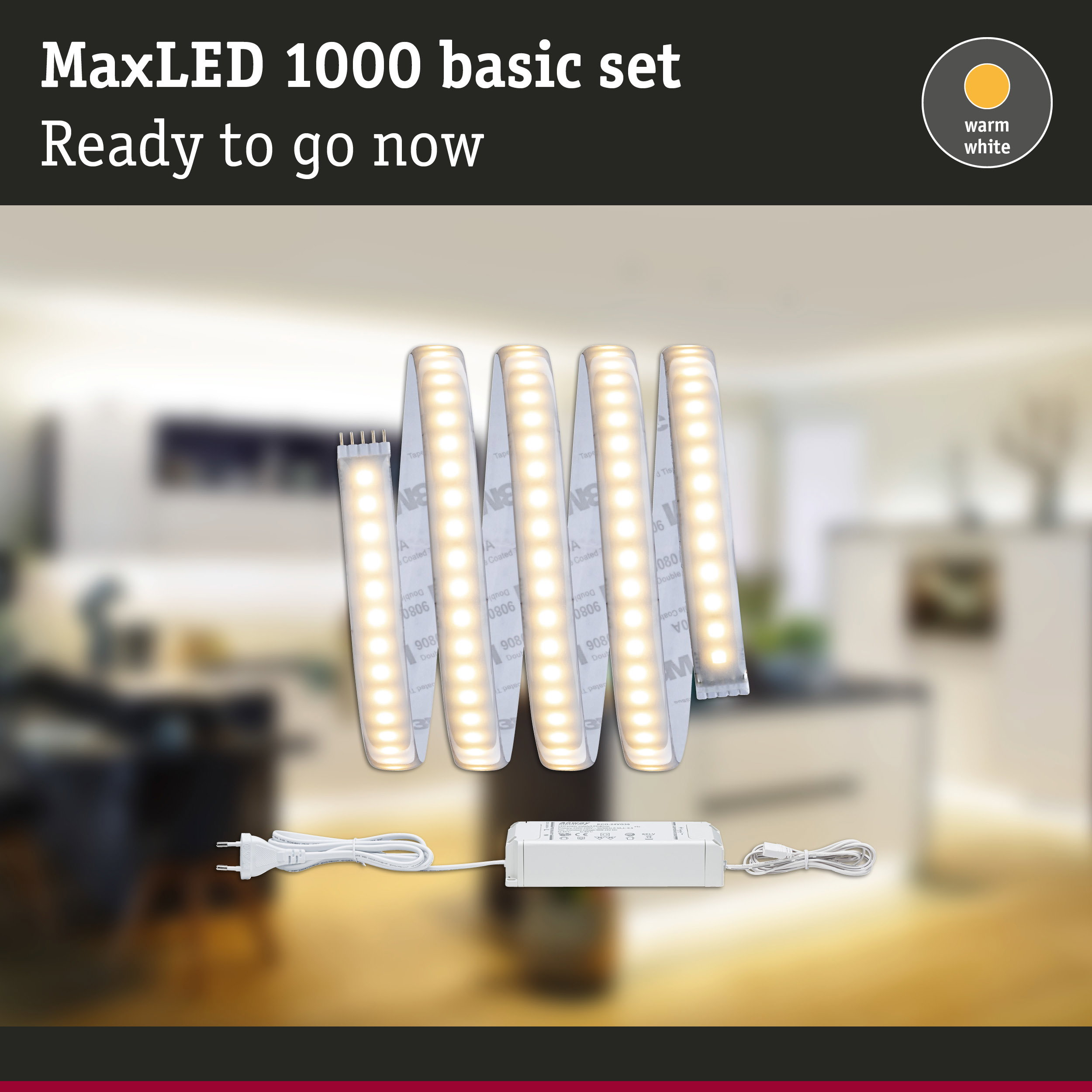 MaxLED 1000 Basisset mit warmweißen LED-Strips, Netzteil und Stecker vor verschwommenem Interieur.