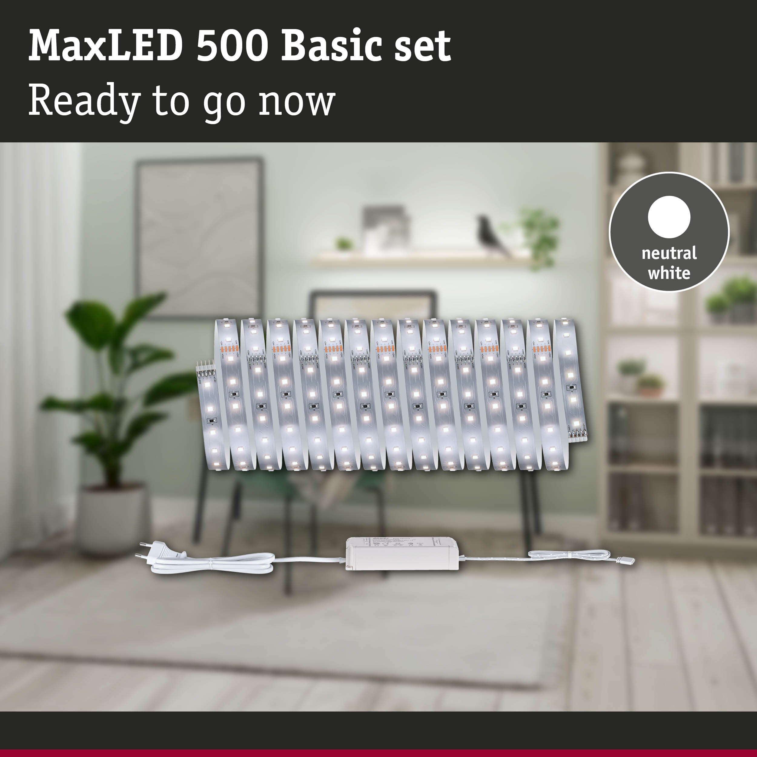 MaxLED 500 Basisset mit neutralweißer LED-Leiste, Netzteil und Stecker vor einem unscharfen Wohnzimmer.