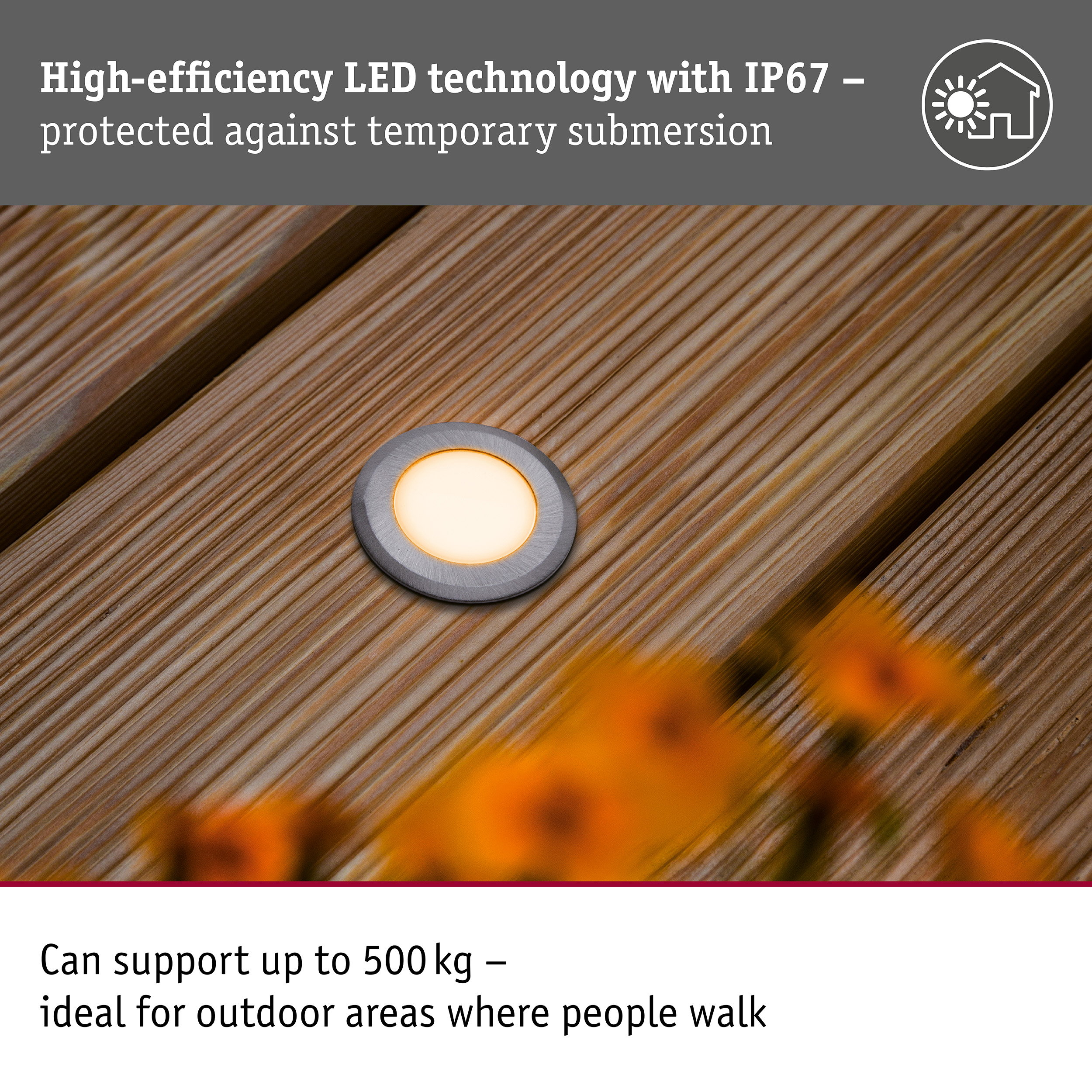 Eine runde LED-Einbauleuchte ist in einen Holzboden eingelassen, umgeben von verschwommenen orangen Blumen.