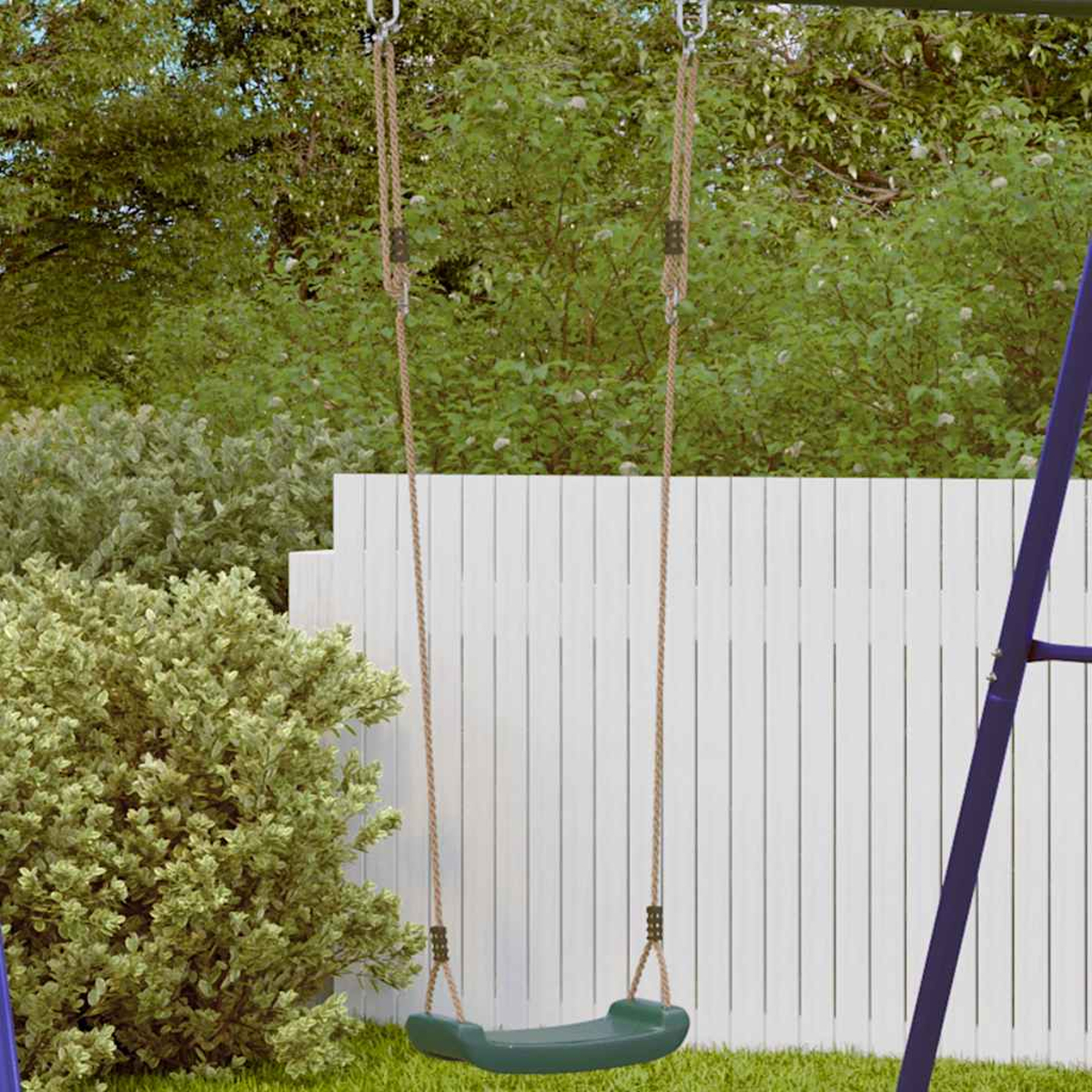 Eine grüne Schaukel mit Seilen hängt im Garten vor einem weißen Holzzaun und Büschen.