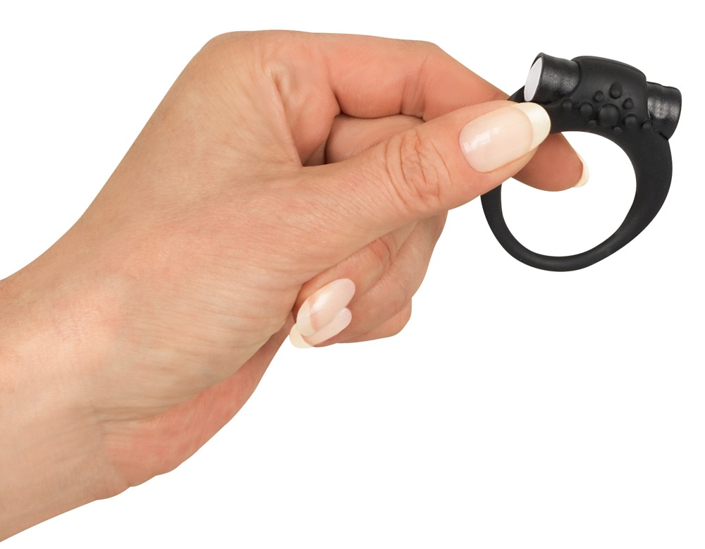 Eine Hand hält einen kleinen, schwarzen Silikonring mit strukturierten Noppen.
