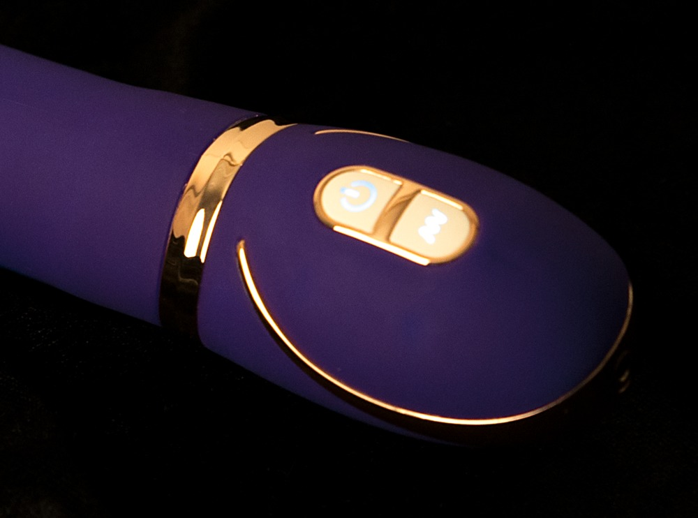 Ein lila vibrator mit goldenen Akzenten und zwei beleuchteten Tasten.