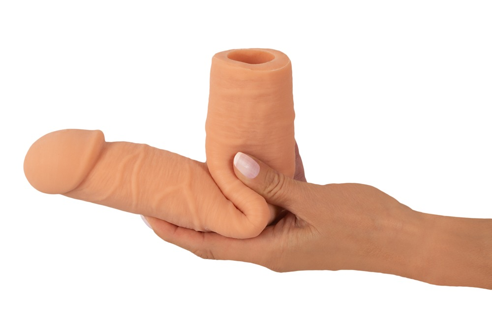 Eine Hand hält ein flexibles, pfirsichfarbenes Silikon-Sexspielzeug vor weißem Hintergrund.