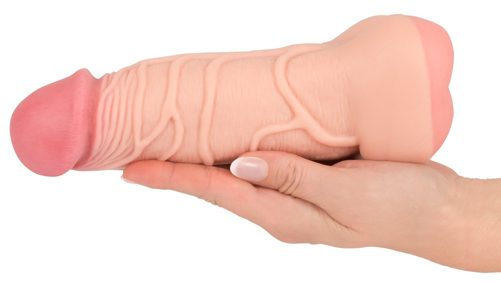 Eine Hand hält einen realistischen, fleischfarbenen Dildo mit sichtbaren Adern vor weißem Hintergrund.