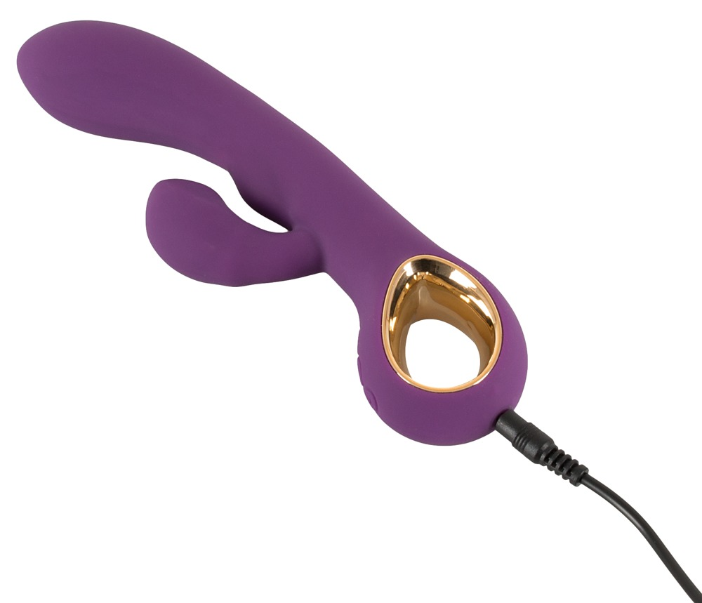 Lila Silikon-Vibrator mit goldenem Ring und angeschlossenem schwarzen Ladekabel auf weißem Hintergrund.