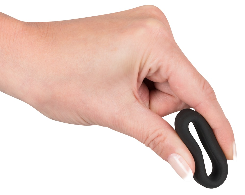Eine Hand hält einen länglichen schwarzen Ring auf weißem Hintergrund.