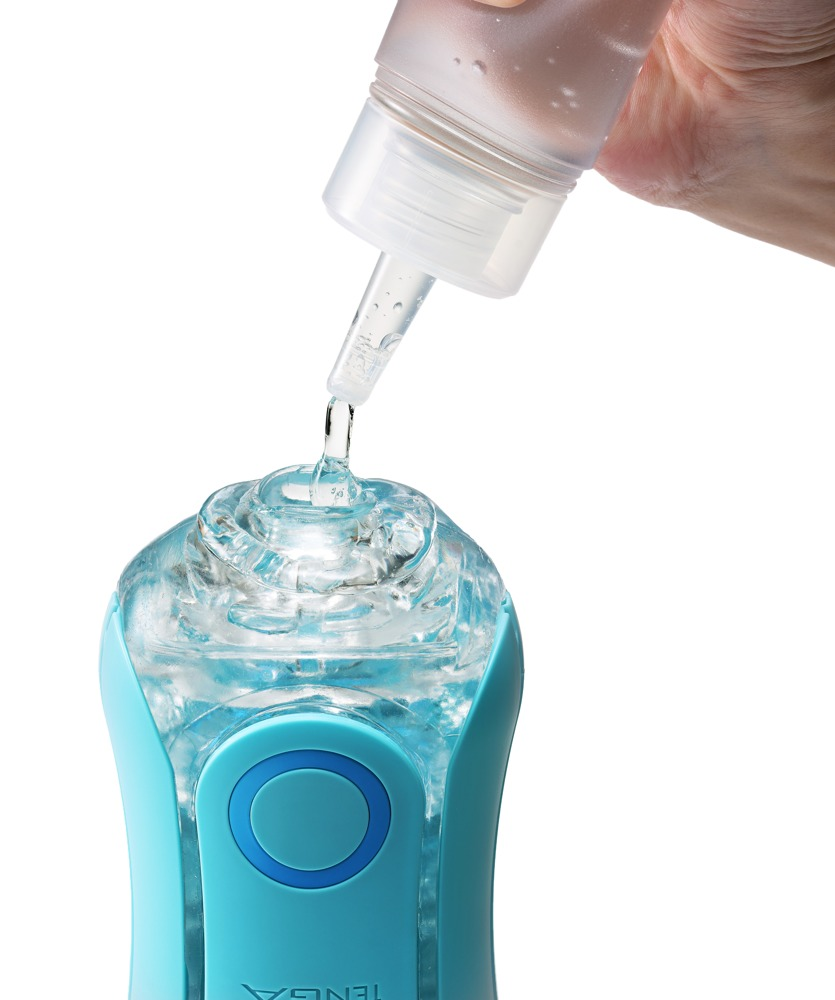 Eine Hand gießt Flüssigkeit aus einer Flasche in eine blaue, glänzende Kapsel.