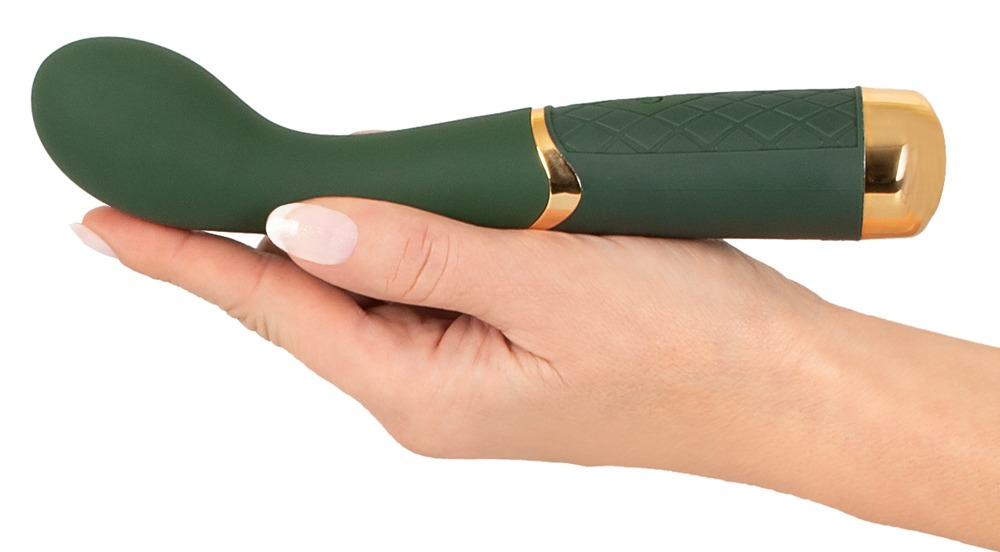 Eine Hand hält ein grünes Wellnessgerät mit goldenen Details und strukturiertem Griff.