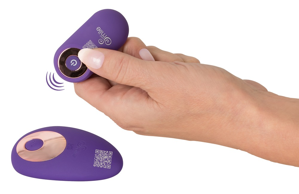 Hand drückt die Taste einer kleinen, violetten Fernbedienung, während eine zweite Fernbedienung unten liegt.
