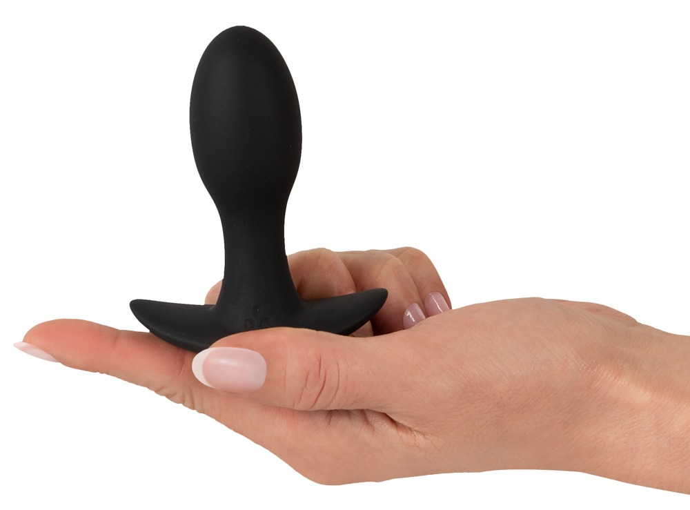 Eine Hand hält ein glattes, schwarzes Wellness-Accessoire in Tropfenform mit flacher Basis.