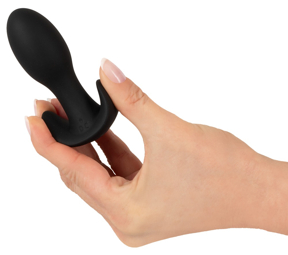 Eine Hand hält ein glattes, schwarzes Wellnessgerät aus Silikon vor weißem Hintergrund.