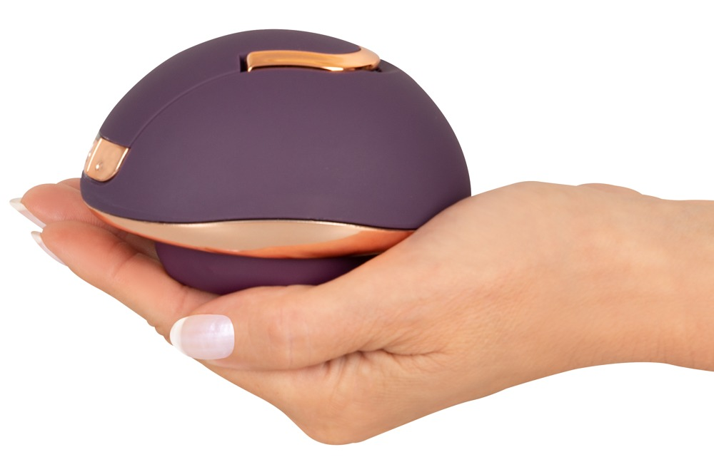 Eine Hand hält ein rundes, dunkelviolettes Objekt mit glänzenden Roségold-Akzenten.