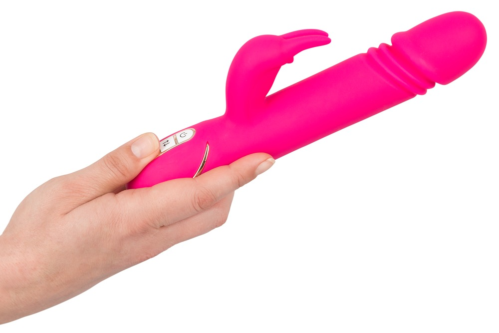 Eine Hand hält ein leuchtend rosa Kaninchen-Vibrator vor weißem Hintergrund.