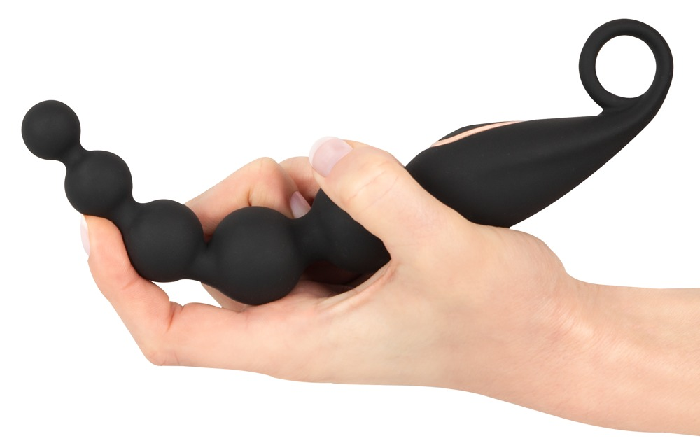 Eine Hand hält ein schwarzes Wellness-Produkt mit Kugeln und Griff.