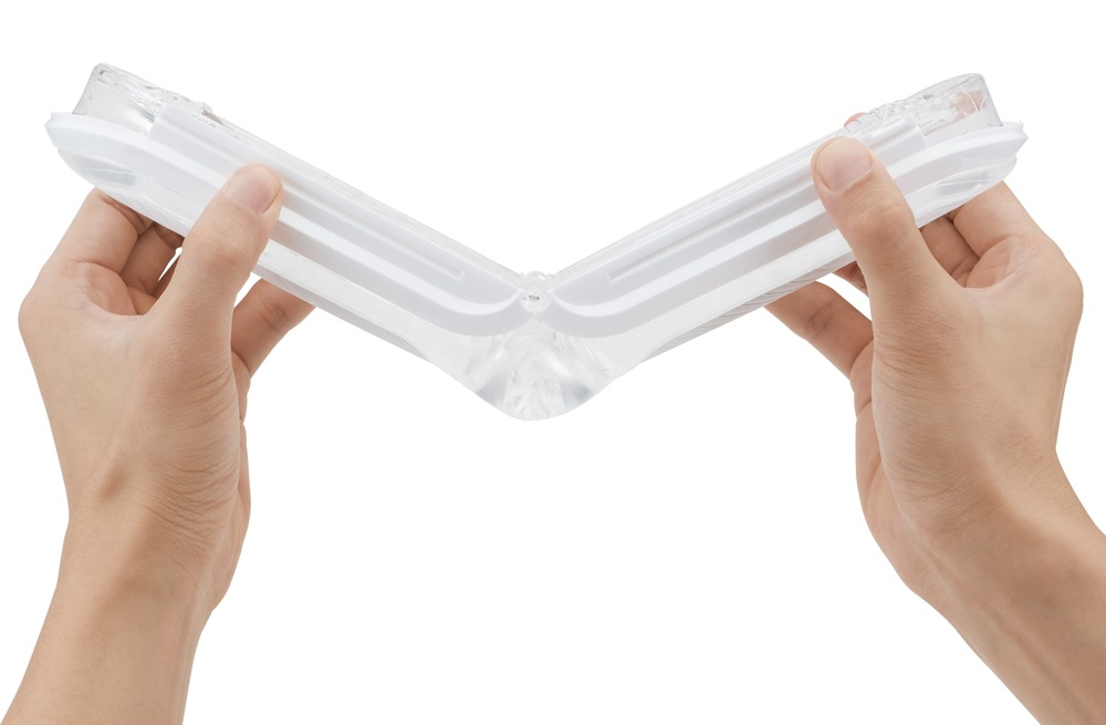 Hände halten eine klare, gefaltete Plastikbox vor weißem Hintergrund.