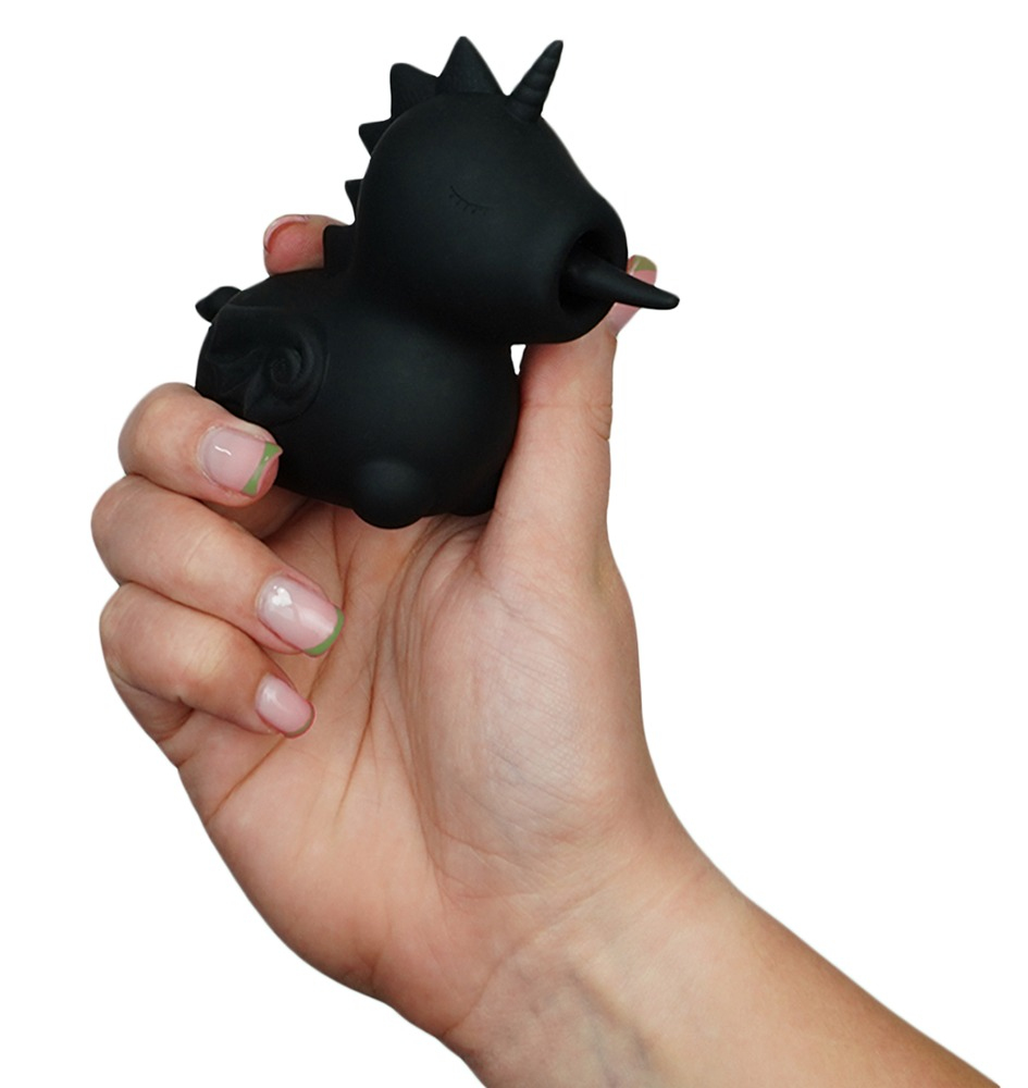Eine Hand hält eine kleine, schwarze Einhornfigur aus Silikon mit offenem Mund gegen einen weißen Hintergrund.
