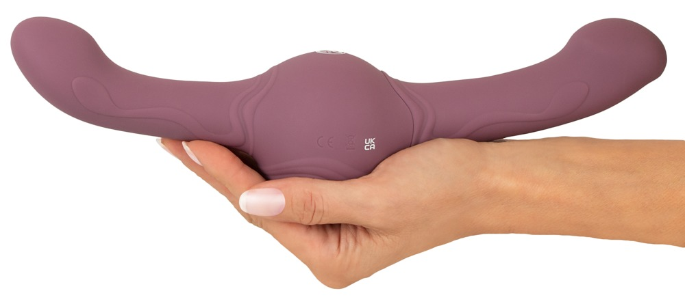 Eine Hand hält ein violettes, Y-förmiges Massagegerät gegen einen weißen Hintergrund.