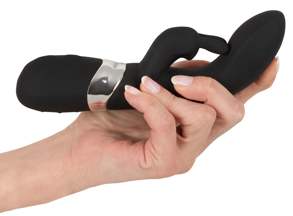 Eine Hand hält einen geschwungenen, schwarzen Vibrator mit silbernen Details vor weißem Hintergrund.
