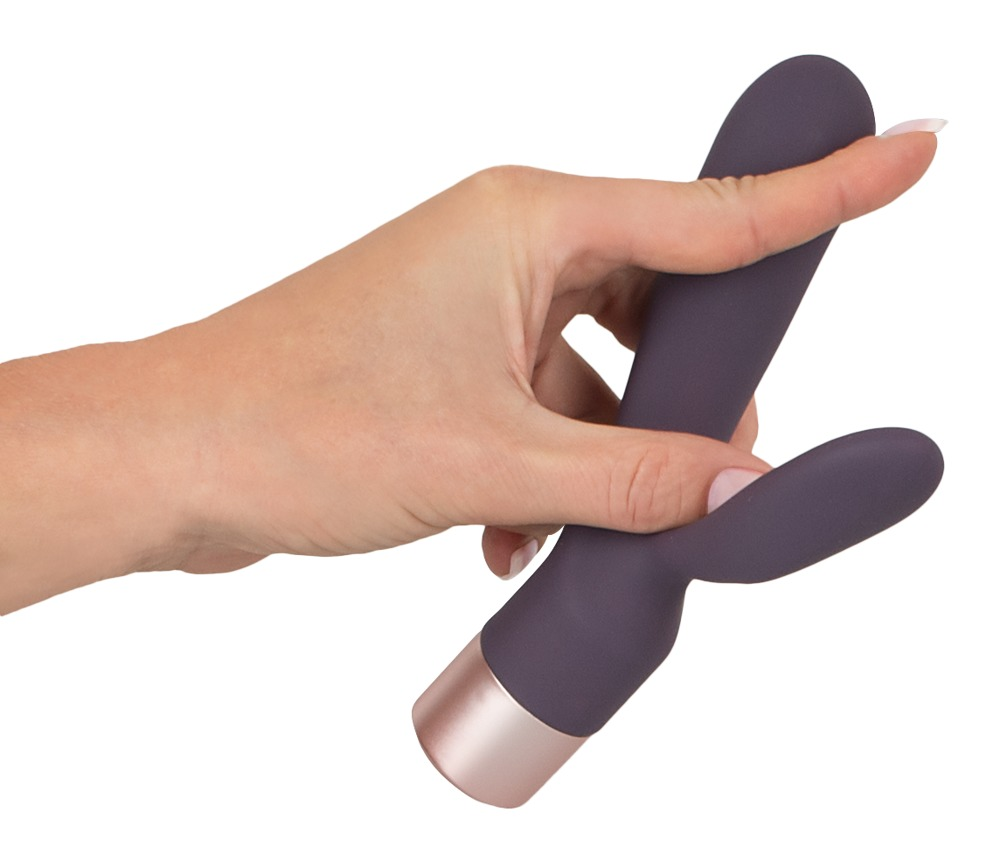Eine Hand hält einen violetten Vibrator mit roségoldenem Sockel.