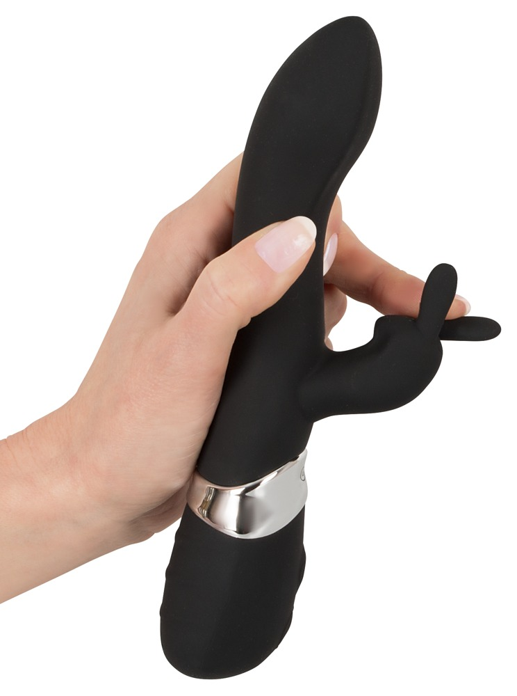 Eine Hand hält ein schwarzes Wellnessgerät mit einem silbernen Ring auf weißem Grund.