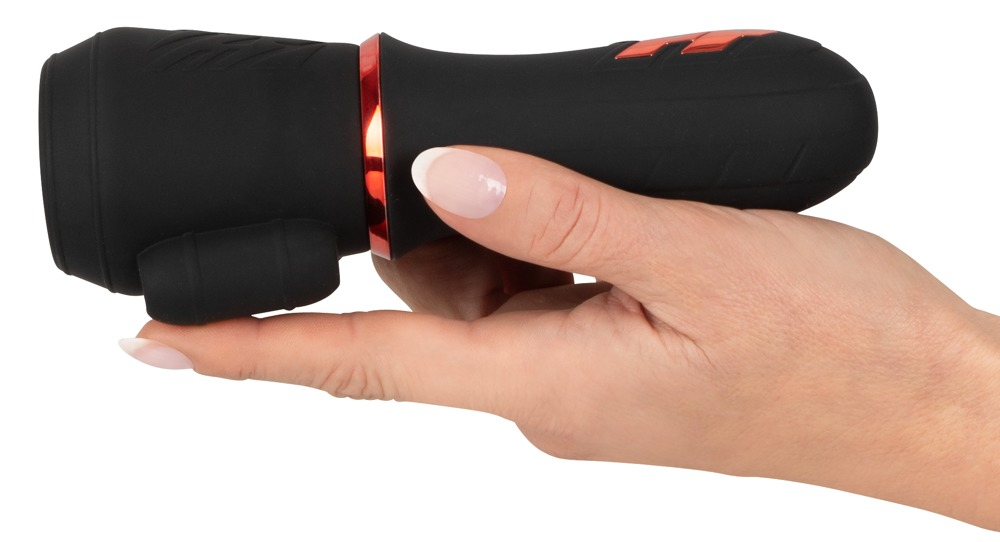 Eine Hand hält ein schwarzes Wellnessgerät mit einem roten Ring gegen weißen Hintergrund.