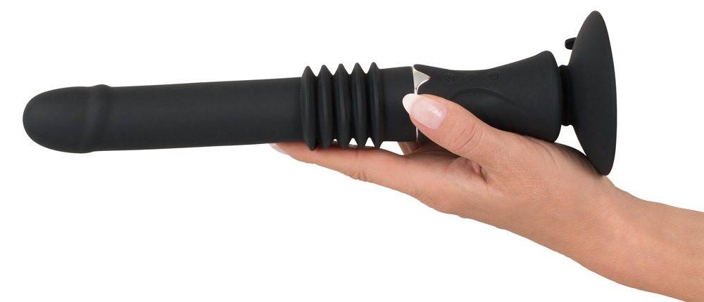 Eine Hand hält ein schwarzes Wellness-Produkt aus Silikon mit Saugfuß vor weißem Hintergrund.