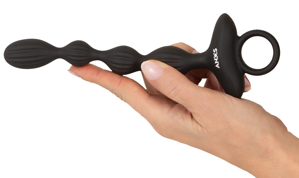 Eine Hand hält ein schwarzes Wellness-Accessoire mit mehreren geriffelten Kugeln und einem Ring am Ende.