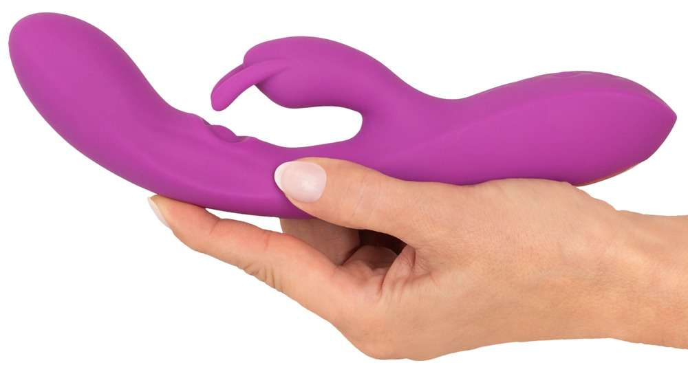 Eine Hand hält ein violettes, geschwungenes Sexspielzeug mit doppelter Stimulation auf weißem Hintergrund.