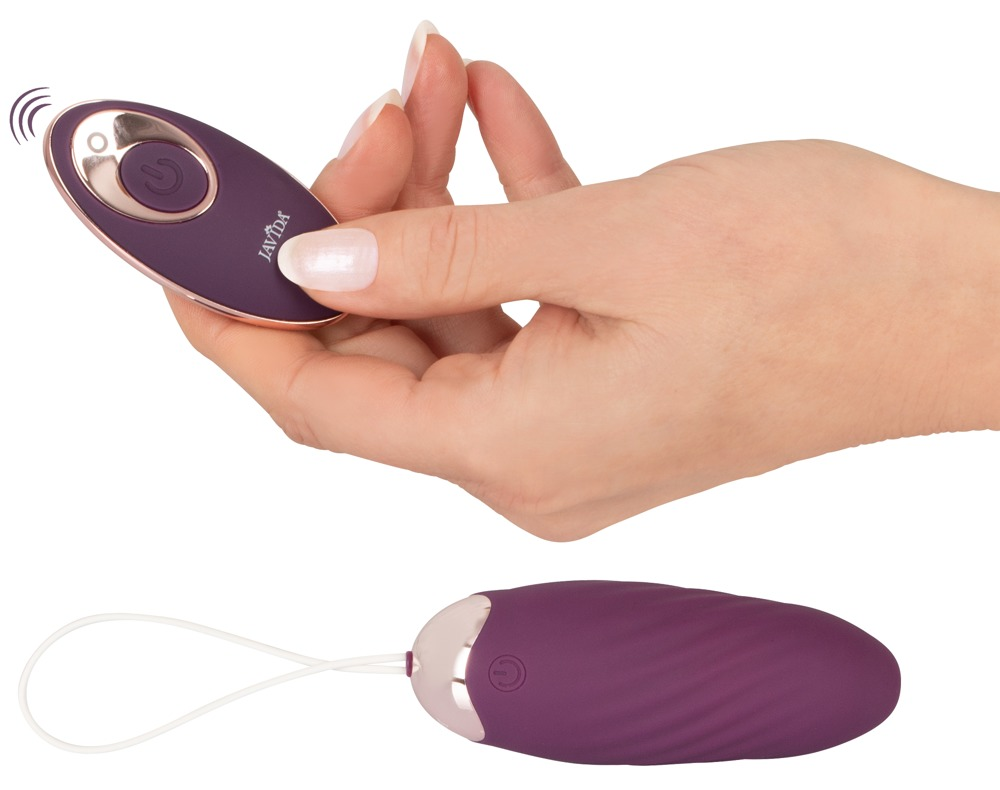 Eine Hand hält eine kleine, ovale, violette Fernbedienung mit kupferfarbenem Rand, unten liegt das passende Gerät mit Kordel.