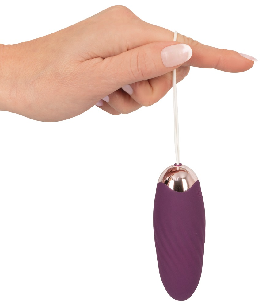 Eine Hand hält einen lila, eiförmigen Vibrator mit weißer Kordel vor weißem Hintergrund.